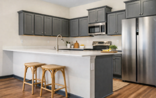 Aspen Kitchen Aspen floor plan kitchen by Maplewood Homes with gray cabinets, large island, stainless steel appliances, and breakfast bar seating