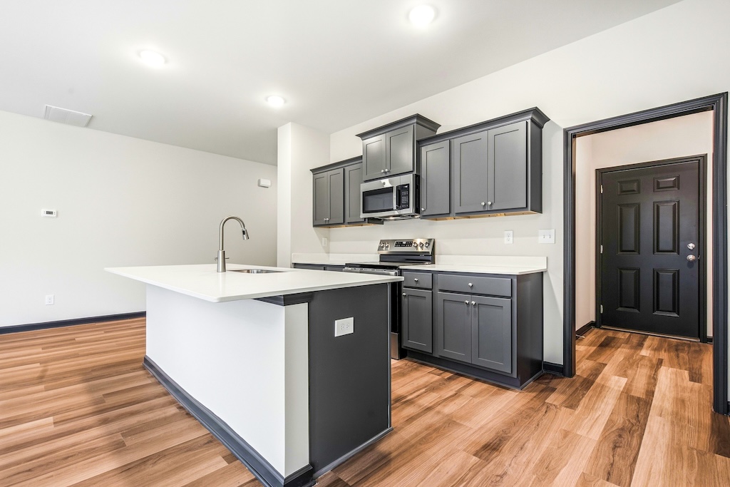 Dexter-21 The Birch floor plan kitchen by Maplewood Homes with oversized island, gray cabinets, and stainless appliances