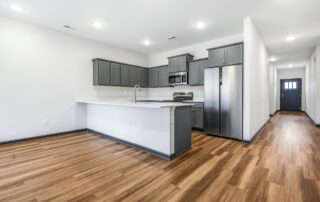 Tercel-5 Aspen floor plan open kitchen and living area by Maplewood Homes with gray cabinets and luxury vinyl plank flooring