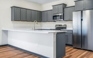 Tercel-6 Aspen floor plan kitchen by Maplewood Homes with gray cabinetry, white countertops, and stainless steel appliances