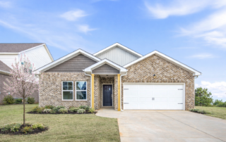 SpruceExterior1 The Spruce floor plan by Maplewood Homes featuring a one-level brick home with covered entry, two-car garage, and spring landscaping.